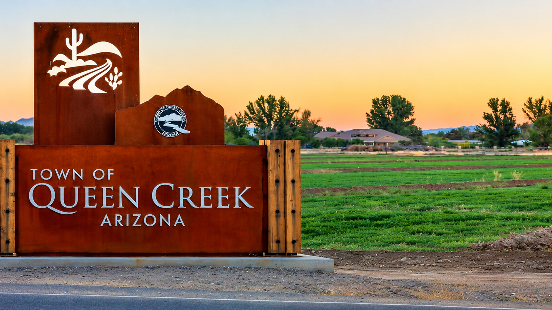 Town of Queen Creek, Arizona welcome sign with farm fields at sunset